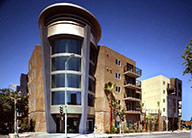 Five-story contemporary stucco building with rounded corner entry and balconies.